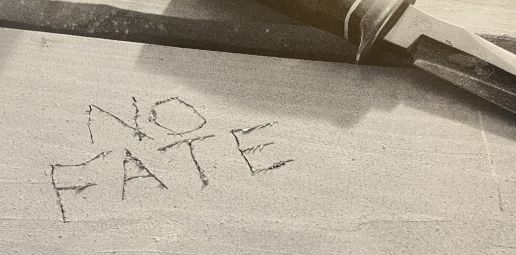 映画ターミネーター２のワンシーン。サラ・コナーが机に刻んだ「NO FATE」の文字。